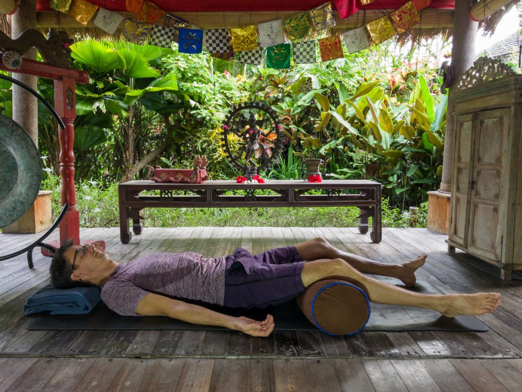 stephen doing savasana with a bolster under his knees