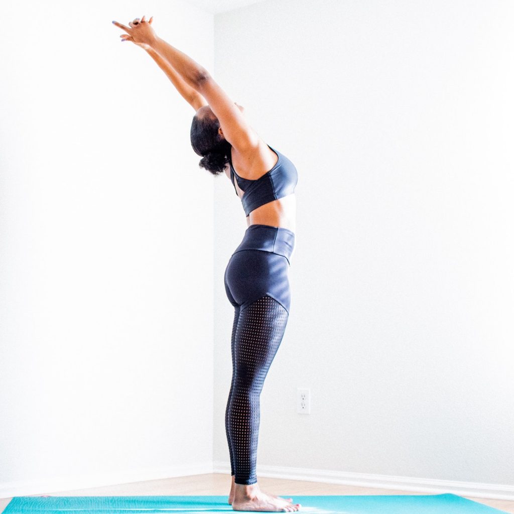 woman doing a standing back bend on a yoga mat