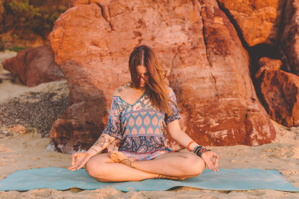 woman sitting in yoga pose on beach